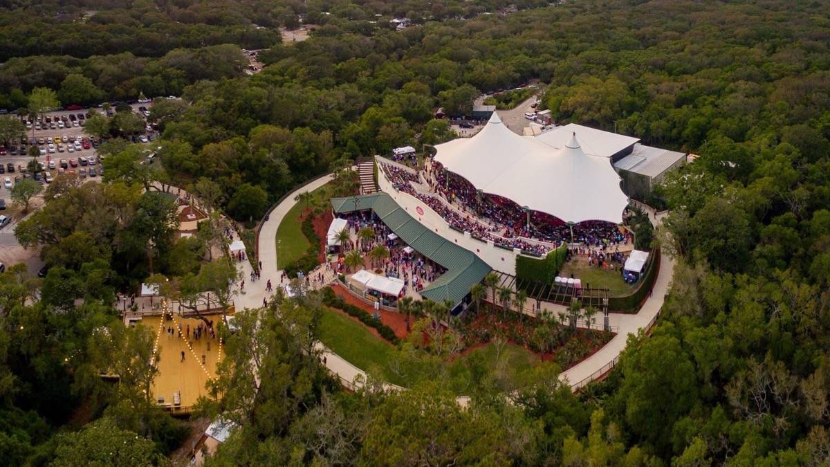 Aerial view of amphitheater with white top surrounded by green forest